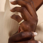 Close-up of a woman wearing a 14k solid yellow gold dome band with rows of pavé set round brilliant cut moissanite stones, luxurious and elegant wedding or statement ring
