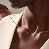 Close-up of a woman wearing a 14k solid yellow gold dot chain necklace with evenly spaced flat square links, styled alone for a simple, modern statement.
