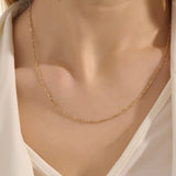 Close-up of a woman wearing a 14k solid yellow gold dot chain necklace with evenly spaced flat square links, styled alone for a simple, modern statement.
