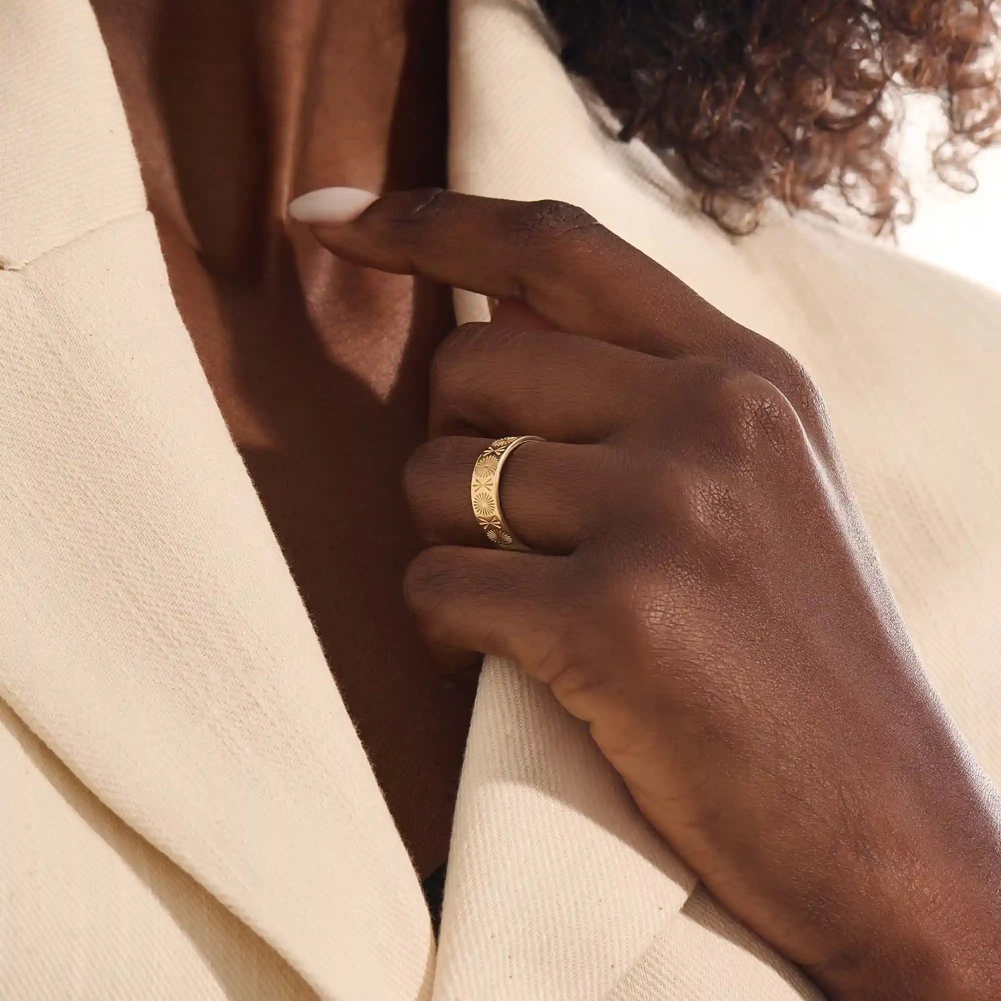 Close-up of a woman wearing a 14k solid yellow gold engraved floral wedding band with intricate detailing
