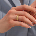 Close-up of a woman wearing a 14k solid yellow gold engraved floral wedding band with intricate detailing
