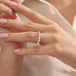 Close-up of a woman wearing a 14k solid yellow gold eternity band with sideways pear cut moissanite stones and pavé set round moissanite accents, ornate and elegant wedding jewelry
