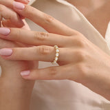 Close-up of a woman wearing a 14k solid yellow gold eternity band with sideways pear cut moissanite stones and pavé set round moissanite accents, ornate and elegant wedding jewelry
