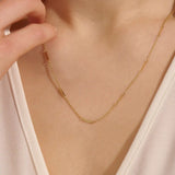 Close-up of a woman wearing a 14k solid yellow gold flat bar chain necklace with evenly spaced polished rectangular accents, styled alone for a refined, modern statement.
