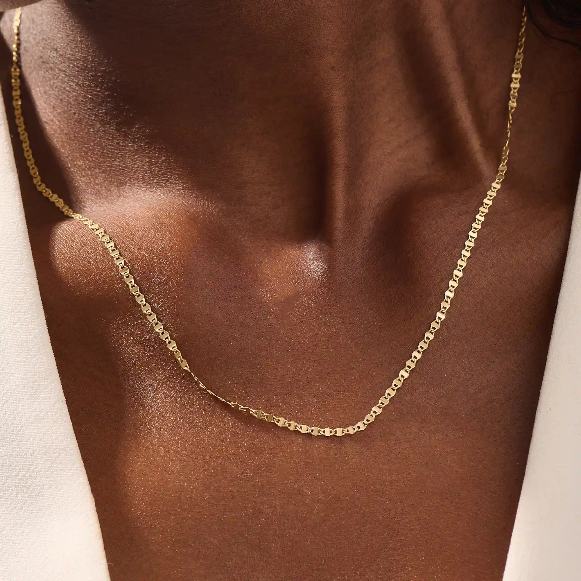 Close-up of a woman wearing a 14k solid yellow gold mariner chain necklace, styled alone to showcase its classic interlocking link pattern and refined shine.
