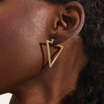 Close-up of a woman wearing a 14k solid yellow gold open triangle hoop earring, its minimalist geometric form making a bold modern statement.
