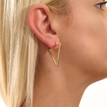 Close-up of a woman wearing a 14k solid yellow gold open triangle hoop earring, its minimalist geometric form making a bold modern statement.

