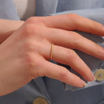 Close-up of a woman wearing a 14k solid yellow gold thin stacking ring with faceted textured design, minimal and elegant everyday jewelry
