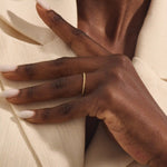 Close-up of a woman wearing a 14k solid yellow gold thin stacking ring with faceted textured design, minimal and elegant everyday jewelry
