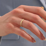 Close-up of a woman wearing a 14k solid yellow gold twisted eternity wedding band with sparkling moissanites in a continuous setting
