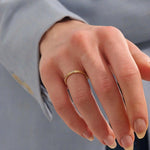 Close-up of a woman wearing a 14k solid yellow gold twisted wedding band with a cluster of round moissanites in a marquise-shaped opening, elegant and timeless
