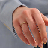 Close-up of a woman wearing a 14k solid yellow gold twisted wedding band with a cluster of round moissanites in a marquise-shaped opening, elegant and timeless
