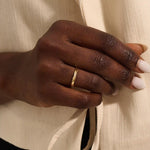Close-up of a woman wearing a 14k solid yellow gold twisted wedding band with a cluster of round moissanites in a marquise-shaped opening, elegant and timeless
