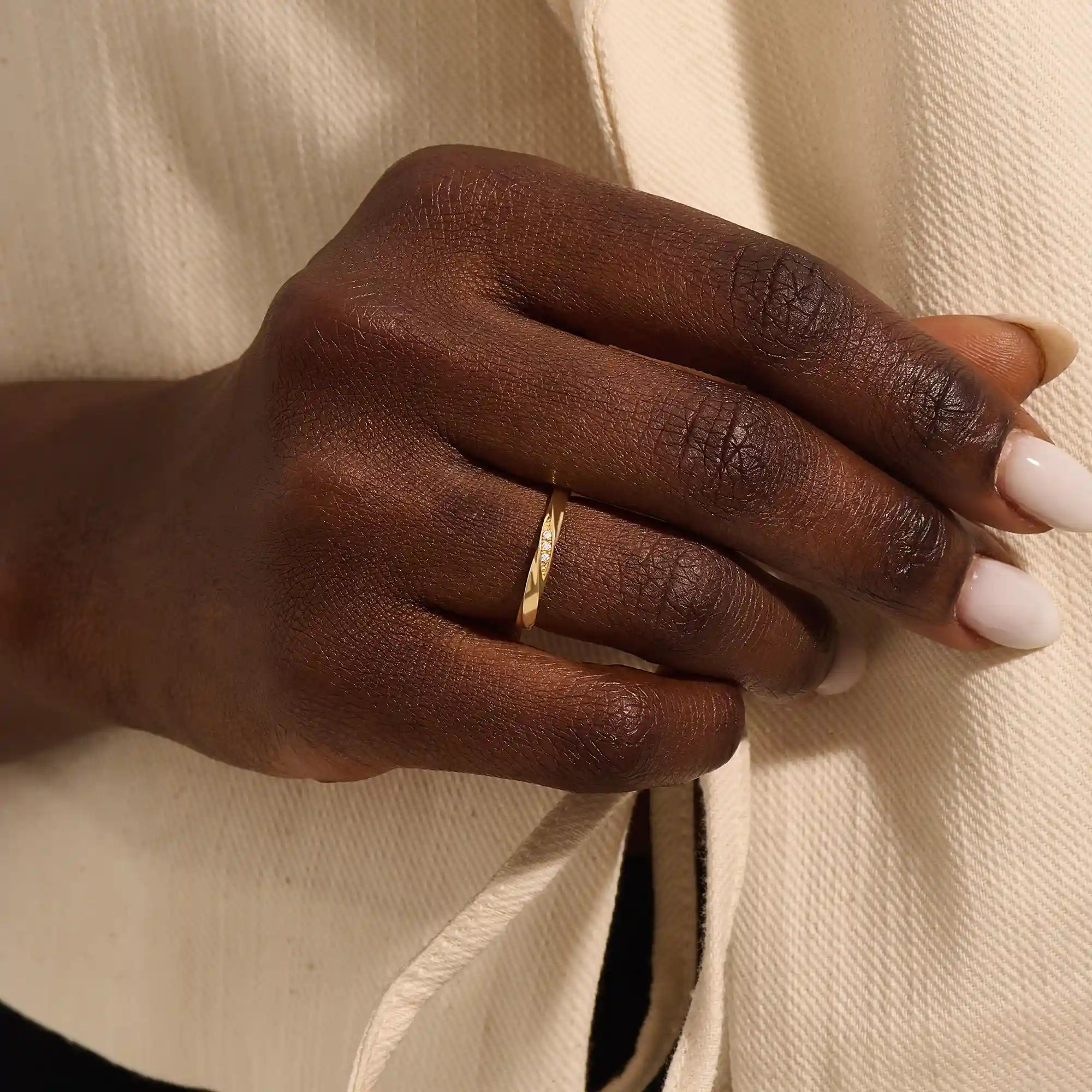 Close-up of a woman wearing a 14k solid yellow gold twisted wedding band with a cluster of round moissanites in a marquise-shaped opening, elegant and timeless
