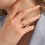 Close-up of a woman wearing a 14k solid yellow gold twisted wedding band with a cluster of round moissanites in a marquise-shaped opening, elegant and timeless
