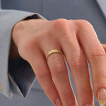 Close-up of a woman wearing a 14k solid yellow gold wedding band with a concentric circle design and bezel-set round moissanites, stylish and distinctive
