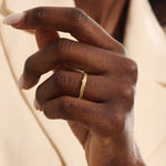 Close-up of a woman wearing a 14k solid yellow gold wedding band with a woodgrain texture, understated and organic style
