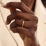 Close-up of a woman wearing a 14k solid yellow gold wedding band with a woodgrain texture, understated and organic style
