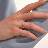 Close-up of a woman wearing a 14k solid yellow gold wedding band with a woodgrain texture, understated and organic style
