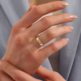 Close-up of a woman wearing a 14k solid yellow gold wide wedding band with baguette moissanite stones in an eternity design
