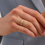 Close-up of a woman wearing a 14k solid yellow gold wide wedding band with baguette moissanite stones in an eternity design
