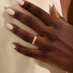 Close-up of a woman wearing a 14k solid yellow gold wide wedding band with baguette moissanite stones in an eternity design
