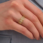 Close-up of a woman wearing a 14k solid yellow gold wide wedding band with moissanite stones in an open lattice setting
