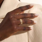 Close-up of a woman wearing a 14k solid yellow gold wide wedding band with moissanite stones in an open lattice setting
