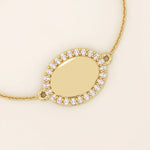 Close-up of an oval gold bracelet highlighting the pavé moissanite halo surrounding the polished oval centerpiece.
