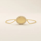 Close-up of an oval gold bracelet highlighting the pavé moissanite halo surrounding the polished oval centerpiece.
