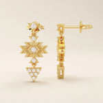 Close-up of dangling motif stud earrings in 14k gold with moissanite set in geometric star and triangle shapes.
