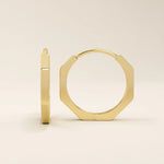 Close-up of small minimal hoop earrings in polished 14k gold with a sleek geometric silhouette.
