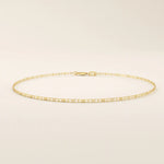 Close-up view of a 14k gold scroll chain bracelet showing the fine engraved rectangular scroll links.
