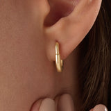 Model wearing 14k gold vermeil oval hoop earrings that combine timeless elegance with a modern oval shape for a polished, statement look.
