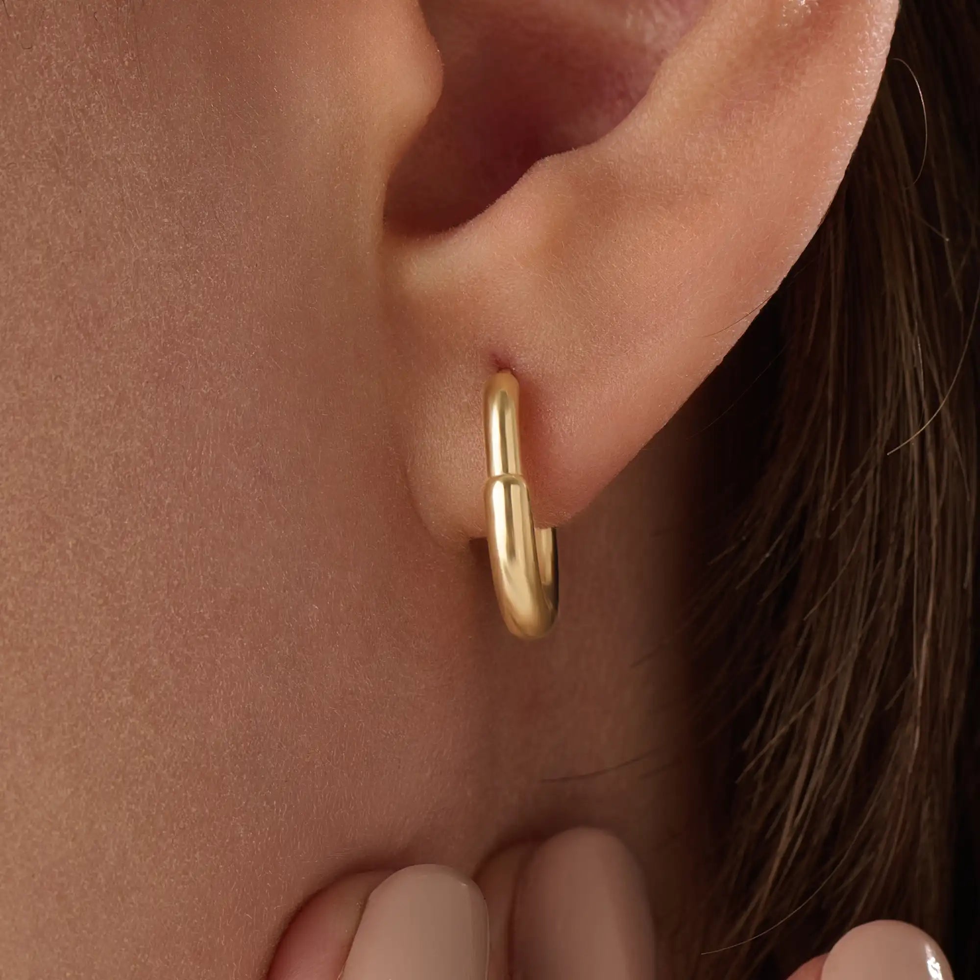 Model wearing 14k gold vermeil oval hoop earrings that combine timeless elegance with a modern oval shape for a polished, statement look.
