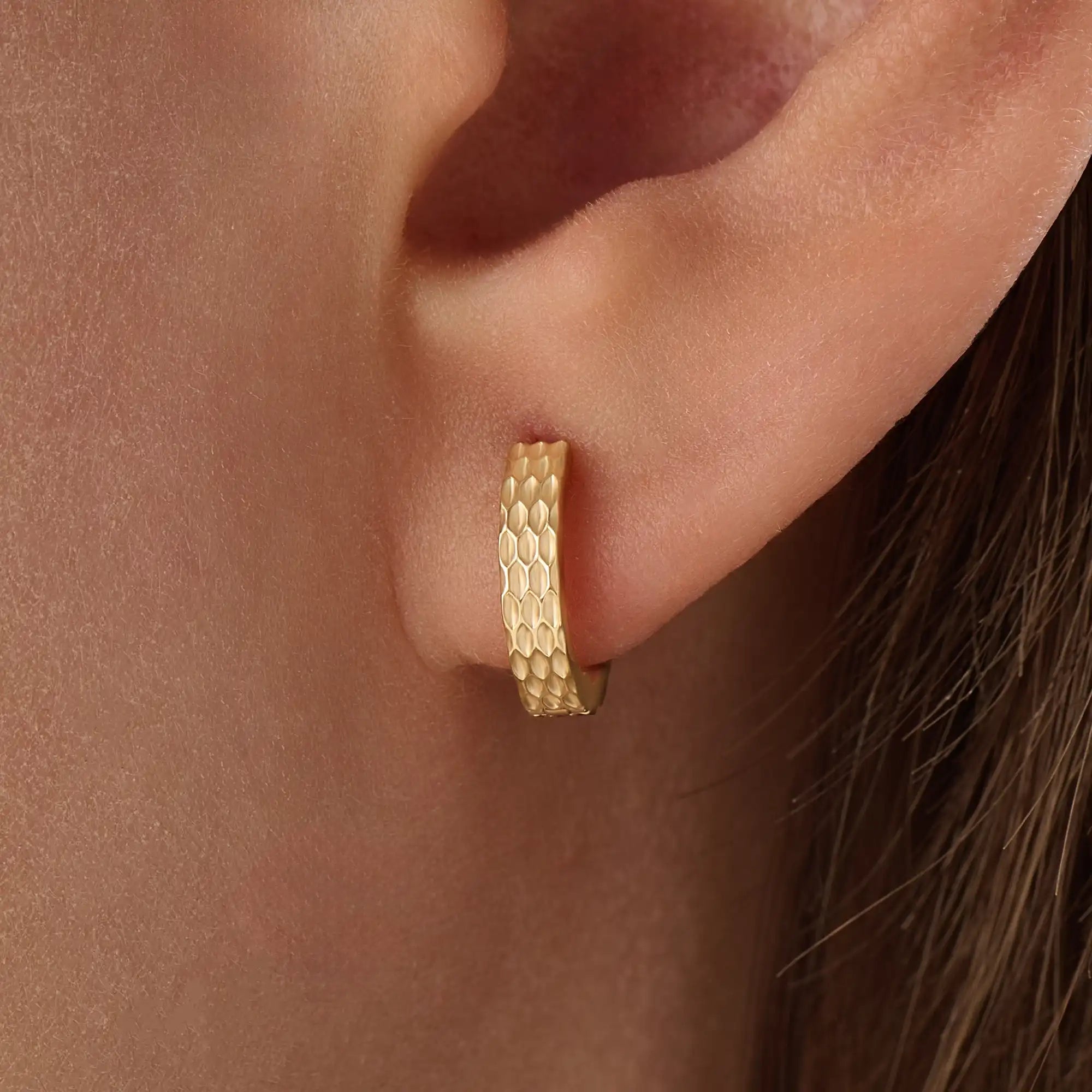 Model wearing 14k gold vermeil textured hoop earrings showcasing their radiant hammered finish that offers a touch of artisanal charm and timeless sophistication.
