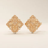 14k rose gold stud earrings shaped like a clover with delicate embossed floral accents and a polished surface.
