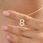 Model showcases a bold pavé initial necklace in 14k gold, sparkling with moissanite stones. Perfect for layering or gifting with impact.