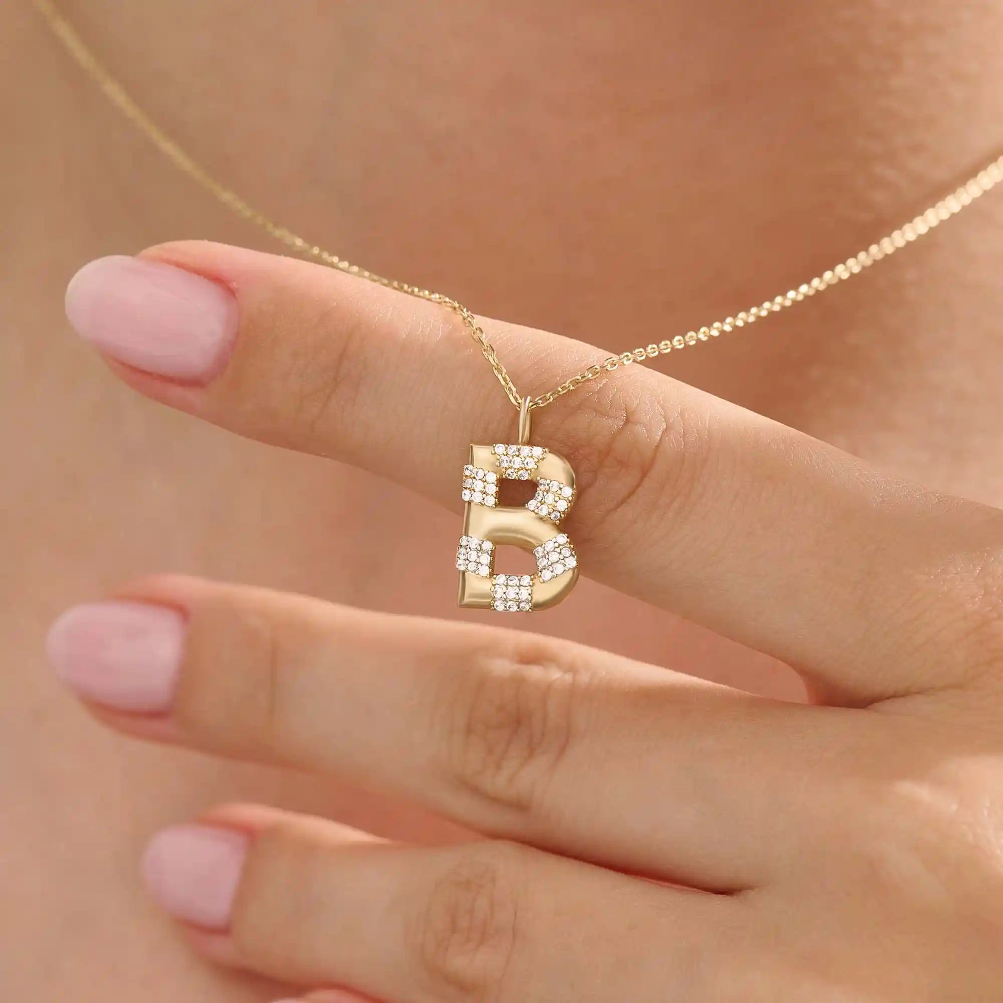 Model showcases a bold pavé initial necklace in 14k gold, sparkling with moissanite stones. Perfect for layering or gifting with impact.