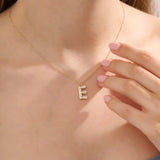 Model showcases a bold pavé initial necklace in 14k gold, sparkling with moissanite stones. Perfect for layering or gifting with impact.