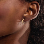 Model wearing 14k gold knot stud earrings, displaying the twisted rope detail and moissanite embellishment on the earlobe.
