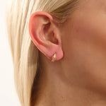 Model wearing 14k gold knot stud earrings, displaying the twisted rope detail and moissanite embellishment on the earlobe.
