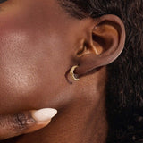 Model wearing 14k gold knot stud earrings, displaying the twisted rope detail and moissanite embellishment on the earlobe.
