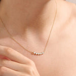 Model wearing 5 stone bezel necklace in 14k gold, showing its elegant horizontal row of bezel-set stones along the neckline.
