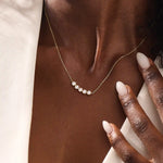 Model wearing 5 stone bezel necklace in 14k gold, showing its elegant horizontal row of bezel-set stones along the neckline.

