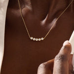 Model wearing 5 stone bezel necklace in 14k gold, showing its elegant horizontal row of bezel-set stones along the neckline.
