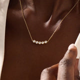 Model wearing 5 stone bezel necklace in 14k gold, showing its elegant horizontal row of bezel-set stones along the neckline.
