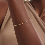 Model wearing a 14k gold bracelet with flat bar segments linked by oval chain for a modern minimalist look.
