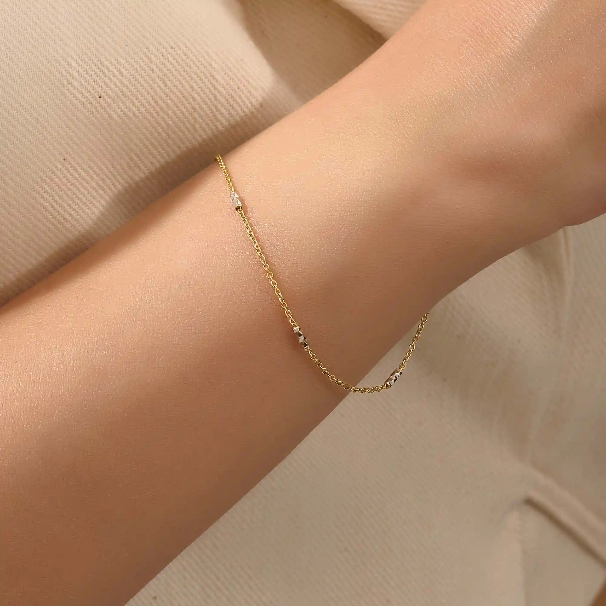 Model wearing a 14k gold bracelet with oval chain links and contrasting mixed-metal bar accents.
