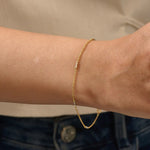 Model wearing a 14k gold bracelet with oval chain links and contrasting mixed-metal bar accents.
